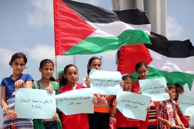 Palestinians children hold placards and wave their national flag during a rally to show support for activists aboard a flotilla of boats who are soon to set sail for Gaza in a fresh bid to break Israel's blockade of the territory