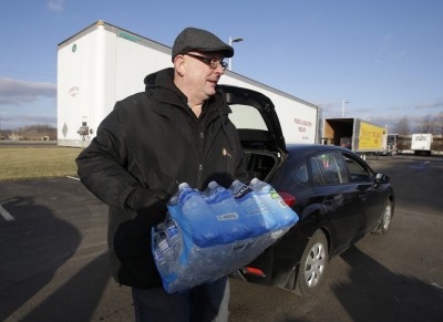 John Whitaker, executive director of Midwest Food Bank, carries a case of water that was donated to Flint residents on January 27. CREDIT: AP Photo/Darron Cummings
